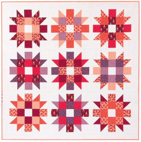 Genny and Ruth quilt with nine large blooming star blocks in warm tones on a soft background