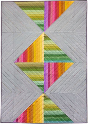 Spectrum Candy quilt, rainbow strip pieced triangles meeting in the centre on a soft grey background