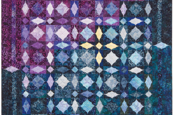 The Lost in the Storm quilt by Shelley Swanland, a square batik quilt in purple and deep blue where every block holds a raised folded lens shape, with three mitered borders