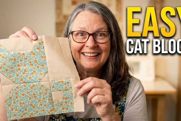 a pieced cat quilt block with ears, head, body and tail made from squares and rectangles