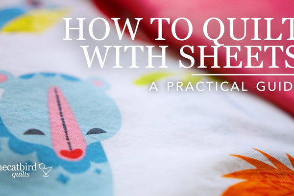 Close up of a printed cotton bed sheet with a blue bear motif, a pink sheet folded behind it