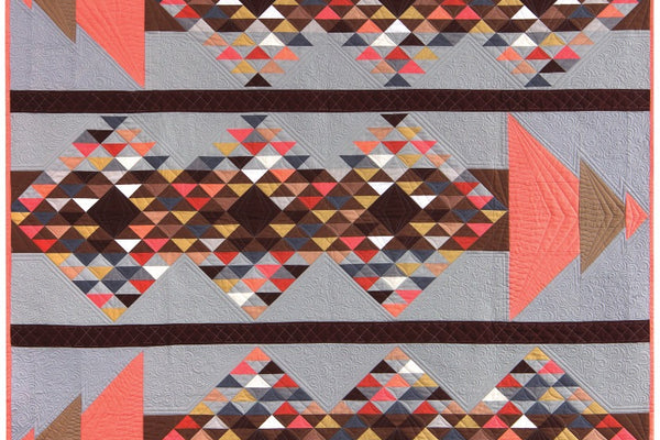 Mosaic quilt by Angela Walters, three gray panel bands of printed triangles with coral and brown pieced arrowheads