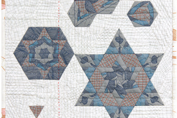 Satellite 5 mini quilt, four English paper pieced rosettes of blue and gray diamonds on a white pieced background