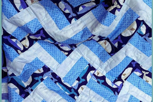 Blue and white rail fence quilt in whale print fabric, quilted with a wavy design