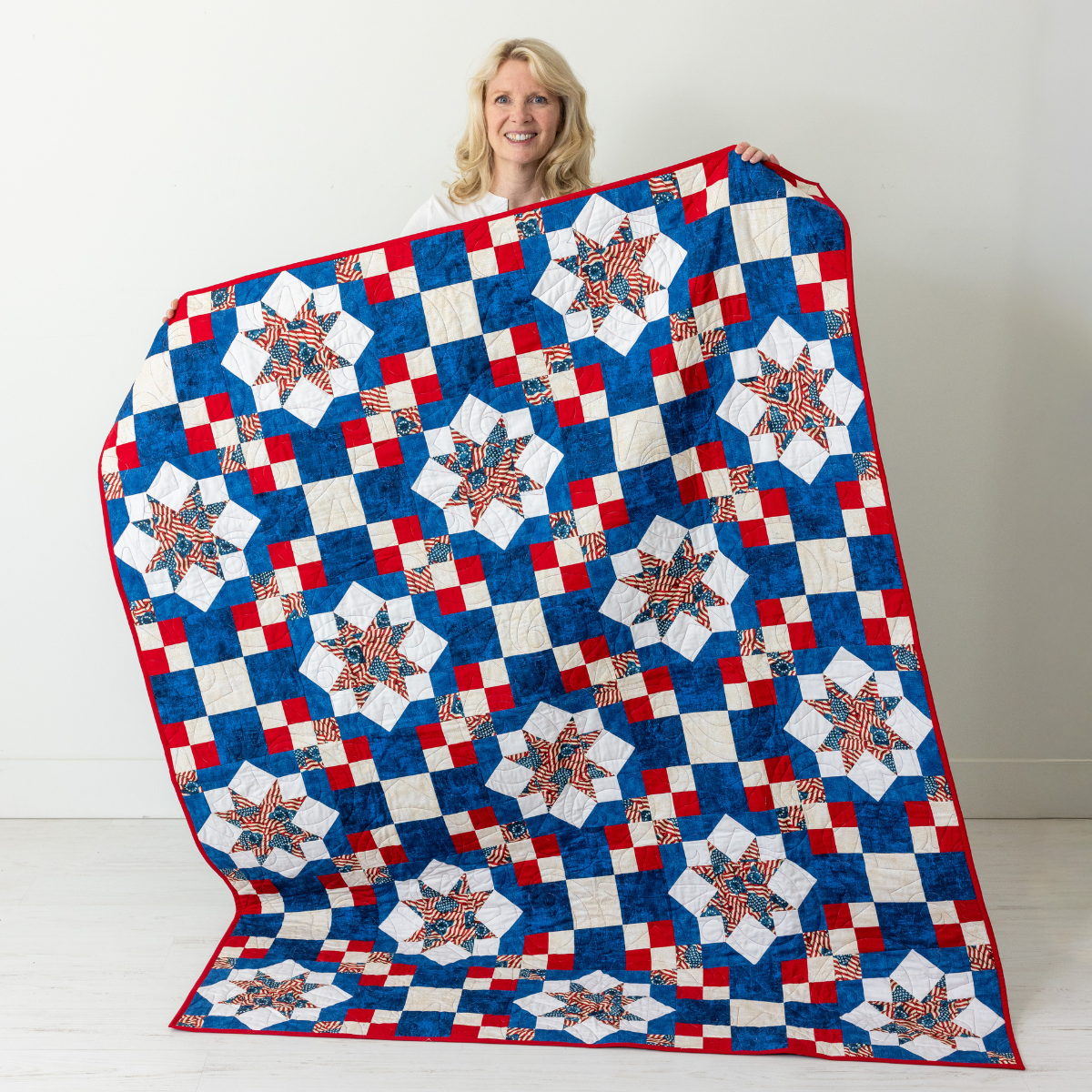 Because of the Brave America 250 quilt held up, red white and blue Sawtooth Star throw from The Fabric Hut kit bundle