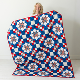 Because of the Brave America 250 quilt held up, red white and blue Sawtooth Star throw from The Fabric Hut kit bundle