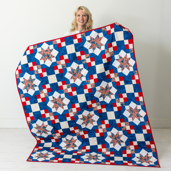 Because of the Brave America 250 quilt held up, red white and blue Sawtooth Star throw from The Fabric Hut kit bundle