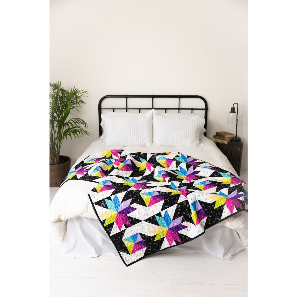 Stars at Sea quilt styled on a bed, modern black and bright star quilt