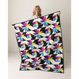 Stars at Sea quilt held up, bright FIGO star quilt on black background from The Fabric Hut kit bundle