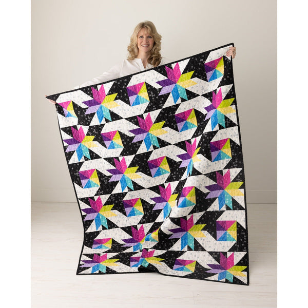 Stars at Sea quilt held up, bright FIGO star quilt on black background from The Fabric Hut kit bundle