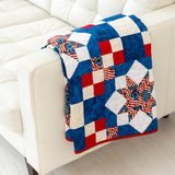 Because of the Brave quilt draped over a cream sofa, red white and blue throw