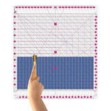 12.5 inch by 12.5 inch slotted quilting ruler, clear acrylic with grooved cutting slots, shown squaring up a quilt block - The Fabric Hut