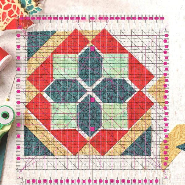 12.5 inch by 12.5 inch slotted quilting ruler, clear acrylic with grooved cutting slots, shown squaring up a quilt block - The Fabric Hut